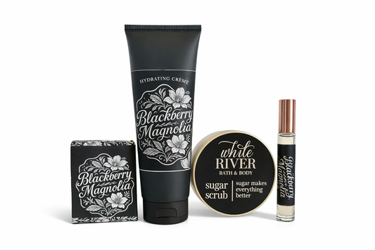 Collection of Blackberry Magnolia skincare products including a tube, bottle, and scrub on a white background.